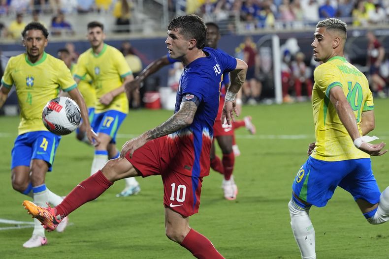 El atacante estadounidense Christian Pulisic (centro) remate entre los brasileños Andreas Pereira (derecha) y Marquinhos (4) durante un partido amistoso, el miércoles 12 de junio de 2024, en Orlando, Florida. (AP Foto/John Raoux)