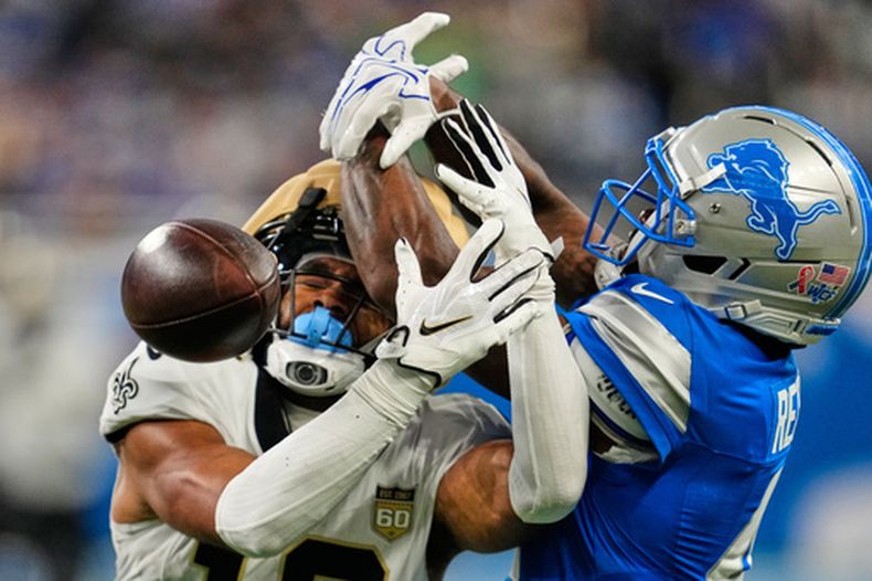 D.J. Reed (4), derecha, de los Lions de Detroit, desvía un pase que buscaba las manos de Chris Olave (12), receptor de los Saints de Nueva Orleans, en la primera mitad del partido de la NFL, el domingo 13 de septiembre de 2026, en Detroit. (AP Foto/Paul Sancya)