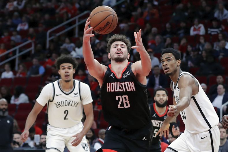Alperen Sengun, de los Rockets de Houston, atrapa un balón perdido entre Cam Johnson (2) y Nic Claxton, de los Nets de Brooklyn, el miércoles 3 de enero de 2024 (AP Foto/Michael Wyke)