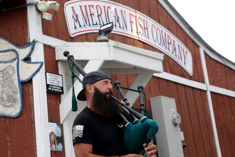 Joey Whitaker from Holden Beach plays Amazing Grace on the bagpipes in front of the American Fish Company following a fatal shooting that occurred here the night before, Sunday, Sept. 28, 2025, in Southport, N.C. (AP Photo/Chris Seward)