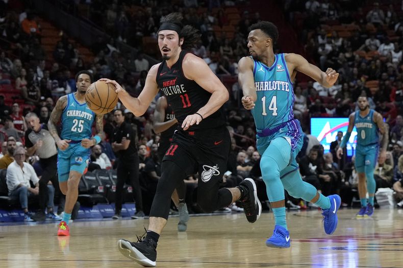 El armador mexicano del Heat de Miami Jaime Jaquez Jr. (11) conduce hacia el aro mientras defiende el base de los Hornets de Charlotte Ish Smith (14) durante la 1ra mitad del juego de baloncesto de la NBA, el domingo 14 de enero de 2024, en Miami. (AP Foto/Lynne Sladky)