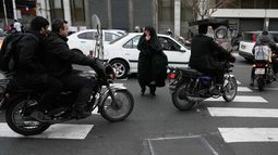 Una mujer cruza una calle mientras las motocicletas pasan en Teherán, Irán, el martes 24 de febrero de 2026. (AP Foto/Vahid Salemi)