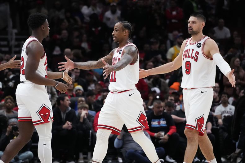DeMar DeRozan (centro) festeja con sus compañeros de los Bulls de Chicago, Nikola Vucevic (derecha) y Terry Taylor, durante el duelo ante los Lakers de Los Ángeles, el miércoles 20 de diciembre de 2023 (AP Foto/Nam Y. Huh)