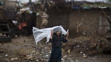americateve | Una chica paquistan&iacute; cuya familia fue desplazada por loe enfrentamientos entre el Talib&aacute;n y el ej&eacute;rcito se cubre de la lluvia con una hoja de pl&aacute;stico en las afueras de Islamabad, Pakist&aacute;n, el martes 25 de marzo de 2014.