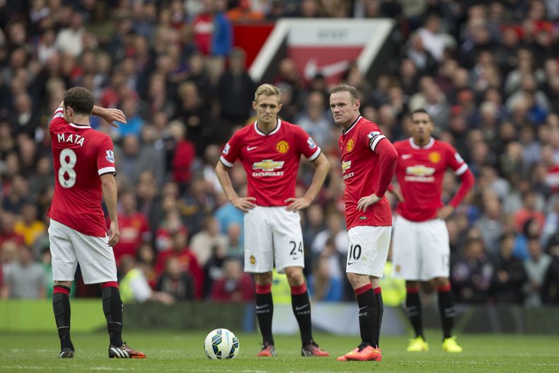 Los jugadores de Manchester United, entre ellos el capit&aacute;n Wayne Rooney, segundo desde la derecha, aguardan para reanudar el partido tras un gol de Swansea en su derrota 2-1 el s&aacute;bado, 16 de agosto de 2014, en Old Trafford. (AP Photo/Jon Sup