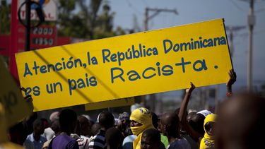 americateve | Manifestantes expresan su descontento ante la decisi&oacute;n de la Rep&uacute;blica Dominicana de retirar la nacionalidad a los hijos de extrajeros que llegaron al pa&iacute;s sin documentos el viernes 6 de diciembre de 2013 en Puerto Pr&iacute;ncipe, Ha