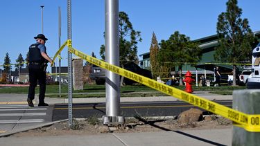 Un agente coloca cinta policial frente a la escuela primaria Silver Rail, donde ocurrió un tiroteo, el jueves 15 de octubre de 2026, en Bend, Oregon. (AP Foto/Joe Kline)