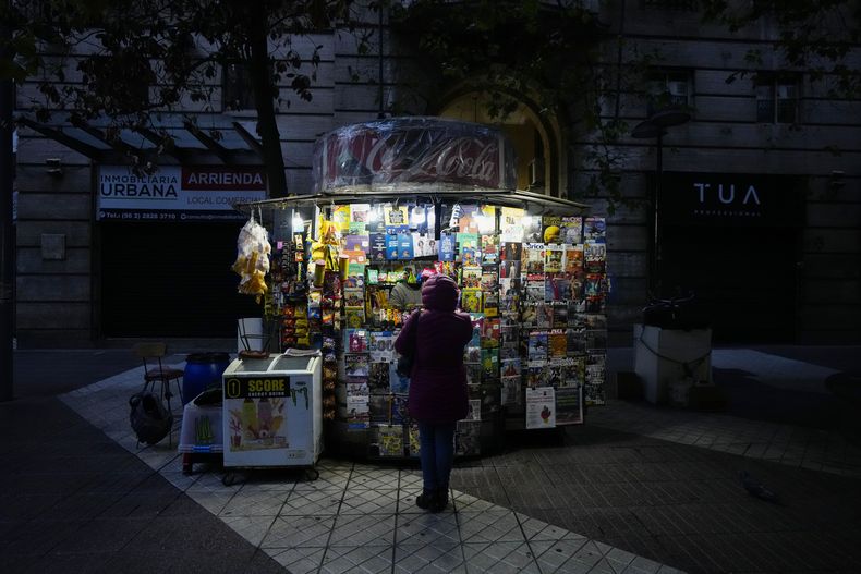 Un cliente con una chaqueta acolchada se para frente a un quiosco, en Santiago, Chile, el viernes 17 de mayo de 2024. (AP Foto/Esteban Félix)