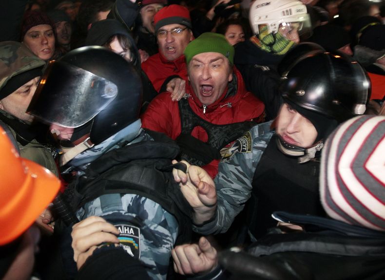 Activistas partidarios de la entrada de Ucrania en la Uni&oacute;n Europea bloquean a la polic&iacute;a antimotines cerca de una estaci&oacute;n policial de Kiev, Ucrania, el s&aacute;bado 11 de enero de 2014. (Foto AP/Serguei Chuzavkov)