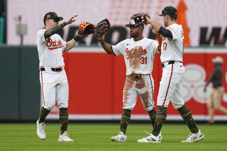 El jardinero izquierdo de los Orioles de Baltimore Austin Hays, la izquierda, el jardinero central Cedric Mullins (31) y el jardinero derecho Colton Cowser (17) celebran después del juego de béisbol contra los Marineros de Seattle, el domingo 19 de mayo de 2024, en Baltimore. (AP Foto/Jess Rapfogel)