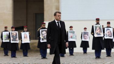El presidente francés Emmanuel Macron camina frente a efectivos de la Guardia Republicana que sostienen retratos de las víctimas francesas del ataque de Hamás del 7 de octubre de 2023 en el monumento Invalides, París miércoles 7 de octubre de 2024. (Gonzalo Fuentes/Pool via AP)