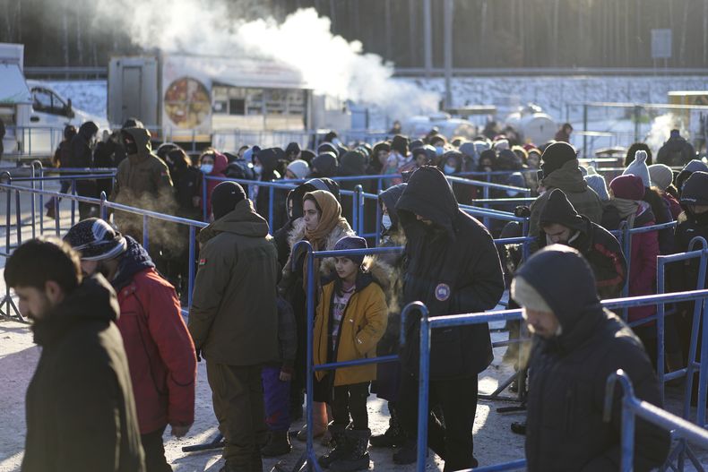 ARCHIVO - Migrantes se forman para recibir comida caliente en un centro de logística en la frontera entre Bielorrusia y Polonia, cerca de Grodno, Bielorrusia, el 22 de diciembre de 2021. (AP Foto/Pavel Golovkin)