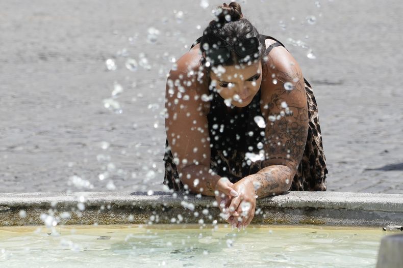 Una mujer se refresca de las altas temperaturas en una fuente en Roma, el 18 de julio de 2023. (AP Foto/Gregorio Borgia)