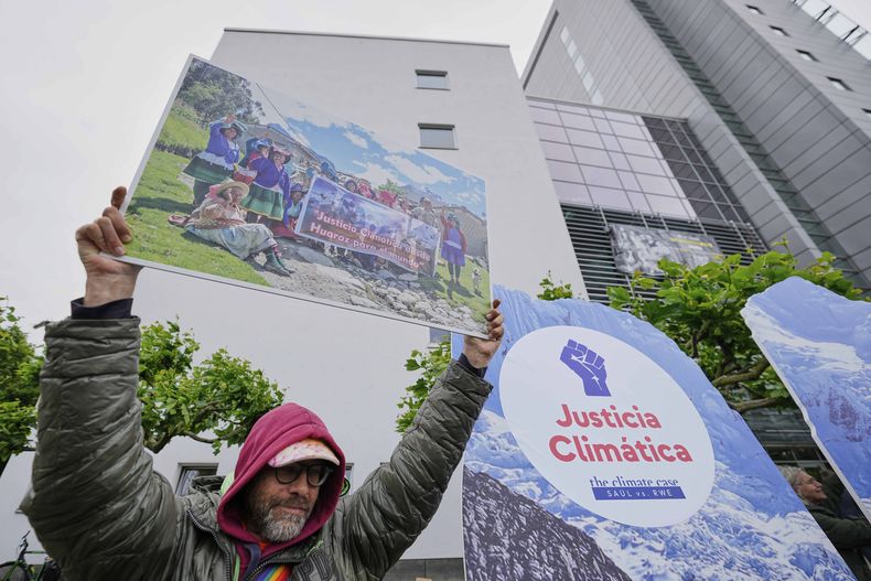 Un manifestante exige justicia climática en el exterior del tribunal superior regional de Hamm, Alemania, antes del veredicto de una demanda climática presentada por el agricultor peruano Luciano Lliuya contra la empresa energética alemana RWE, el 28 de mayo de 2025. (AP Foto/Martin Meissner)