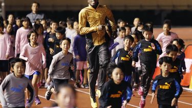 americateve | El velocista jamaiquino Usain bolt corre con ni&ntilde;os en una actividad el viernes, 22 de noviembre de 2013, en Tokio. (AP Photo/Shuji Kajiyama)