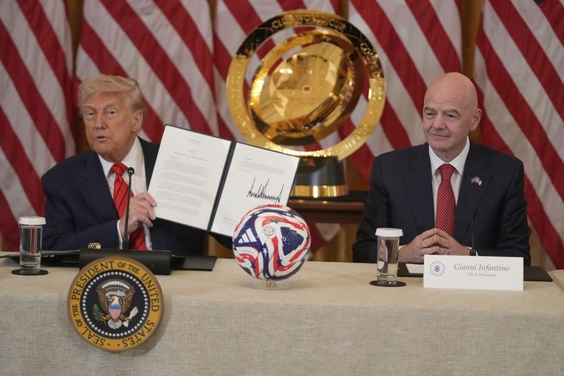 ARCHIVO - El presidente de Estados Unidos Donald Trump sostiene la orden ejecutiva que crea el grupo de trabajo encargado de supervisar los preparativos de la Copa Mundial 2026, acompañado por el presidente de la FIFA, Gianni Infantino, el martes 6 de mayo de 2025, en la Casa Blanca. (AP Foto/Mark Schiefelbein)
