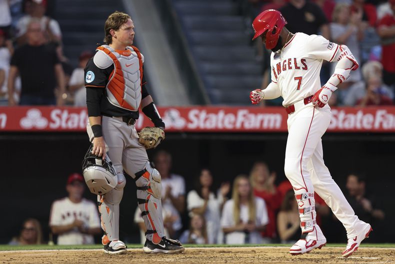 Jo Adell (7), de los Angelinos de Los Ángeles, llega al plato después de conectar un jonrón mientras el receptor de los Orioles de Baltimore, Adley Rutschman, a la izquierda, observa durante la cuarta entrada de un juego de béisbol en Anaheim, California, el sábado 10 de mayo de 2025. (AP Foto/Jessie Alcheh)