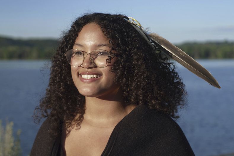 Jayvionna Buck posa para un retrato a orillas del río Mississippi con la nueva pluma de águila que recibió, en una ceremonia en honor de graduados de la secundaria como ella, el miércoles 9 de julio de 2025, en la Comunidad Indígena de la Isla Prairie, en Minnesota. (AP Foto/Mark Vancleave)