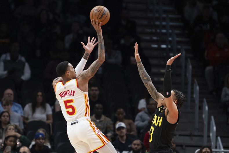 Dejounte Murray, base de los Hawks de Atlanta, dispara desde la distancia de tres puntos ante Keyonte George, del Jazz de Utah, el martes 27 de febrero de 2024 (AP Foto/Hakim Wright Sr.)