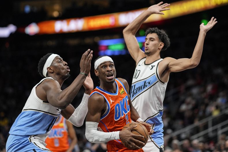 Shai Gilgeous-Alexander, base del Thunder de Oklahoma City, elude a Zaccharie Risacher (derecha), de los Hawks de Atlanta, en el encuentro del viernes 28 de febrero de 2025 (AP Foto/Mike Stewart)