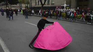 Juan Pablo Vargas hace movimientos del toreo con un capote en una protesta en la que defensores y críticos de las corridas de todos se reunieron a las afueras de la Suprema Corte, en Ciudad de México, el miércoles 6 de diciembre de 2023. La Suprema Corte de México tenía previsto decidir si reactivaba las corridas en la capital, un año después de que fueran prohibidas. (AP Foto/Fernando Llano)