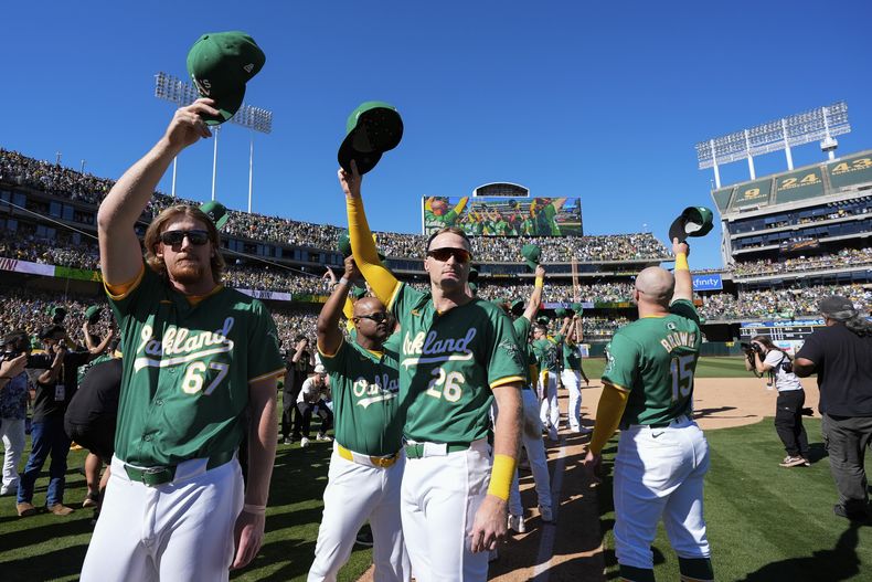 Grant Holman (67) y Tyler Nevin (26), de los Atléticos de Oakland, se despiden del público de esta ciudad, tras disputar su último juego ahí, ante los Rangers de Texas, el jueves 26 de septiembre de 2024 (AP Foto/Godofredo A. Vásquez)