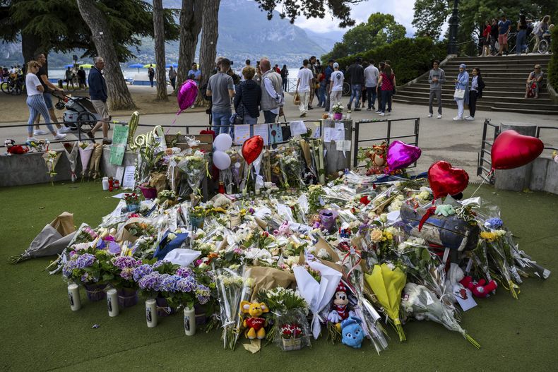Un grupo de flores, juguetes de peluche y mensajes de apoyo forman un monumento improvisado en la superficie acolchada de un patio de recreo infantil en Annecy, Francia, el sábado 10 de junio de 2023, donde cuatro niños pequeños y dos adultos fueron heridos a puñaladas el jueves y tuvieron que ser hospitalizados. (Jean-Christophe Bott/Keystone vía AP)