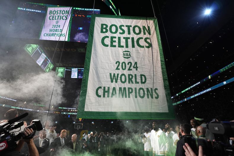El banderín conmemorativo del 18vo título de los Celtics de Boston en la NBA es izado antes del partido inaugural de la nueva campaña ante los Knicks de Nueva York, el martes 22 de octubre de 2024 (AP Foto/Charles Krupa)