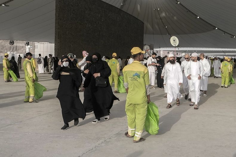 Personal de limpieza forma una fila frente a los peregrinos que vienen de arrojar piedras a un pilar en el apedreo simbólico del demonio, último rito de la peregrinación anual del Hajj, en Mina, cerca de la ciudad santa de La Meca, Arabia Saudí, 28 de junio de 2023. (AP Foto/Amr Nabil)