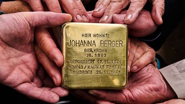 Familiares sujetan el bloque que dice en alemán Johanna Berger, nacida en 1893, vivió aquí. Fue deportada el 17 de noviembre de 1941, asesinada el 25 de noviembre de 1941 en Kowno/Kaunas Fort IX, enfrente de su antigua vivienda en Berlín, Alemania, el 6 de mayo del 2026. (AP foto/Markus Schreiber)