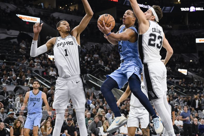 Desmond Bane, de los Grizzlies de Memphis, salta a la cesta entre victor Wembanyama y Zach Collins, de los Spurs de San Antonio, en el encuentro del sábado 18 de noviembre de 2023 (AP Foto/Darren Abate)