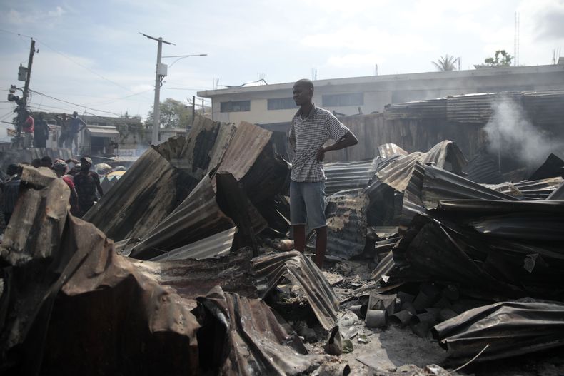 Un vendedor observa a los bomberos trabajar para extinguir un incendio en el mercado Shada en el área de Petion-ville en Puerto Príncipe, Haití, el jueves 4 de mayo de 2023. (Foto AP/Odelyn Joseph)