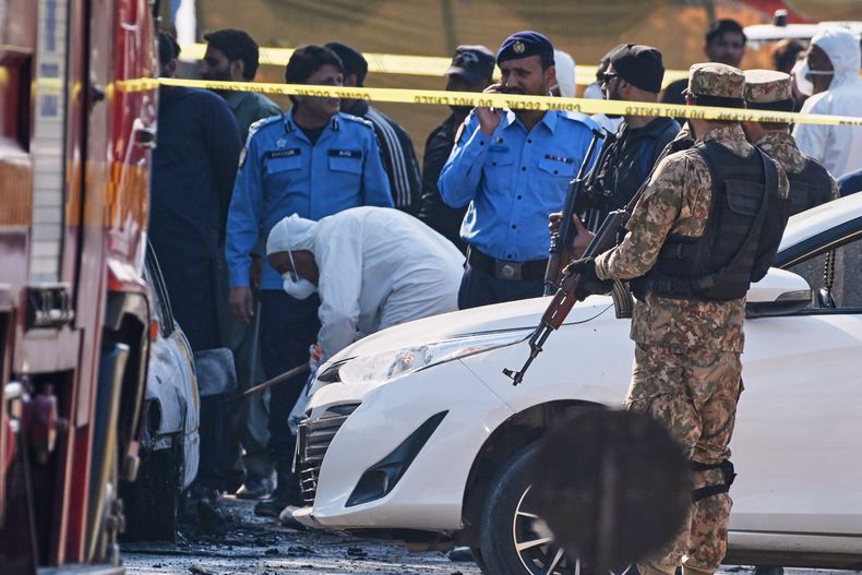 Investigadores paquistaníes examinan un auto dañado en el sitio donde ocurrió un ataque suicida fuera de las puertas de un tribunal de distrito en Islamabad, Pakistán, el martes 11 de noviembre de 2025. (AP Foto/Ahsan Shahzad)