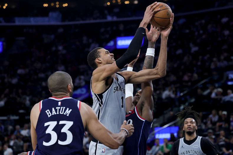 Victor Wembanyama, centro, de los Spurs de San Antonio, busca disparar ante Bennedict Mathurin, centro derecha, y Nicolas Batum (33), de los Clippers de Los Ángeles, durante la primera mitad del juego de baloncesto de la NBA, el lunes 16 de marzo de 2026, en Inglewood, California. (AP Foto/Ryan Sun)