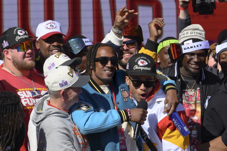 El cornerback LJarius Sneed, centro, de los Chiefs de Kansas Cuty, abraza a su compañero de posición Trent McDuffie, mientras ambos hablan con los fanáticos durante el desfile de celebración del campeonato del Super Bowl, en Kansas City, Missouri, el miércoles 14 de febrero de 2024. Sneed recibió la etiqueta de jugador franquicia sin derechos exclusivos el lunes 4 de marzo de 2024. (AP Foto/Reed Hoffmann)