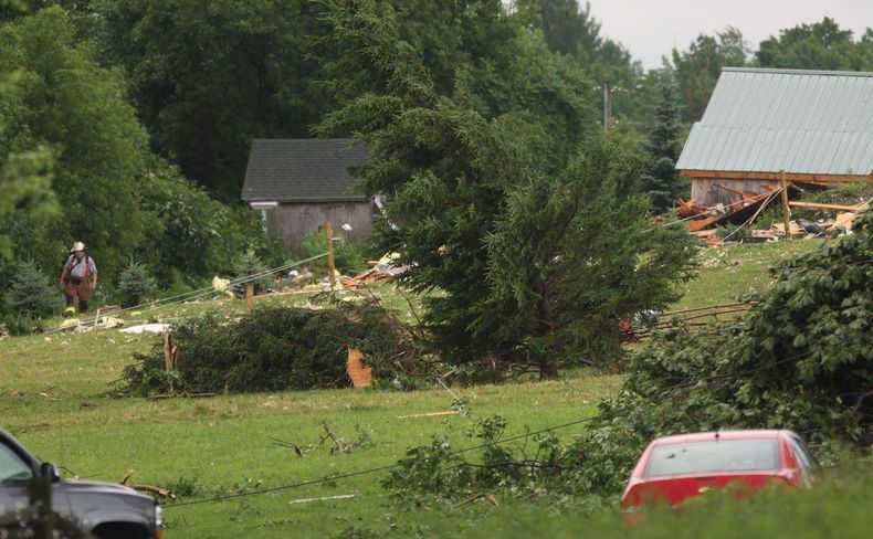 Un bombero camina entre escombros junto a la carretera Goff Road en Smithfield, Nueva York, tras una tormenta el martes, 8 de julio del 2014.(Foto AP/Oneida Daily Dispatch, John Haeger)