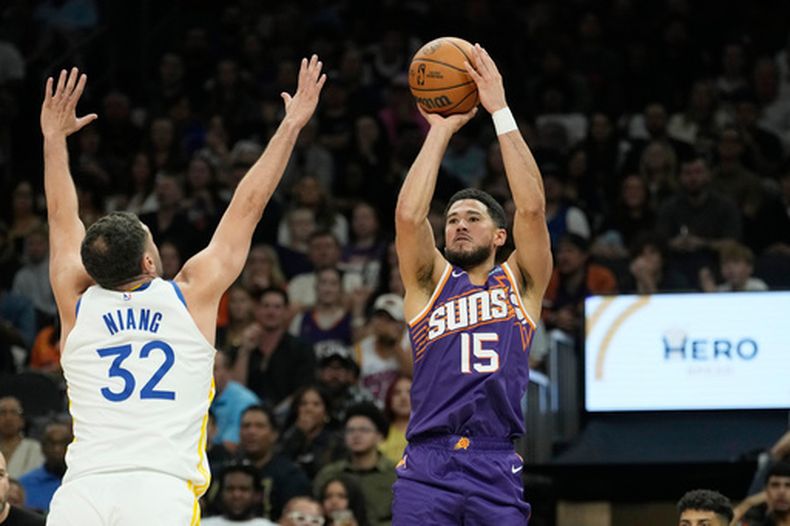 El guardia de los Suns de Phoenix, Devin Booker (15), realiza un tiro de tres puntos por encima del delantero de los Warriors de Golden State, Georges Niang (32), durante un partido de básquetbol de la NBA, el sábado 24 de octubre de 2026, en Phoenix. (Foto AP/Ross D. Franklin)
