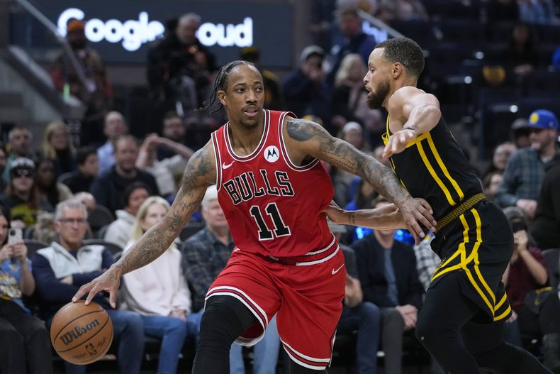DeMar DeRozan, alero de los Bulls de Chicago, trata de eludir a Stephen Curry, de los Warriors de Golden State, en el encuentro del jueves 7 de marzo de 2024 (AP Foto/Godofredo A. Vásquez)