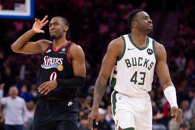 Tyrese Maxey, izquierda, de los 76ers de Filadelfia, reacciona tras acertar un triple mientras Thanasis Antetokounmpo, de los Bucks de Milwaukee, observa durante la segunda mitad del juego de baloncesto de la NBA, el domingo 12 de abril de 2026, en Filadelfia. (AP Photo/Chris Szagola)