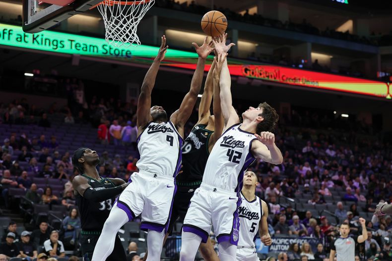 Precious Achiuwa (9) y Maxime Raynaud (42), de los Kings de Sacramento, disputan un rebote frente a Joan Beringer, centro, durante la segunda mitad del juego de baloncesto de la NBA, el domingo 9 de noviembre de 2025. (AP Foto/Sara Nevis)