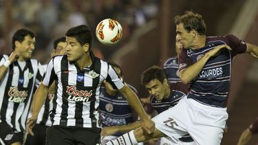 americateve | Leandro Somoza, del club argentino Lan&uacute;s, derecha, disputa el bal&oacute;n con Jorge Recalde del Libertad de Paraguay, durante su juego de vuelta de las semifinales de la Copa Sudamericana, el jueves 28 de noviembre de 2013, en Buenos Aires, Argent