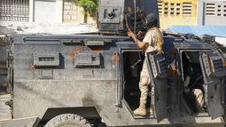 La policía se cobija durante una operación antipandillas en Puerto Príncipe, Haití, el viernes 1 de marzo de 2024. (AP Foto/Odelyn Joseph)