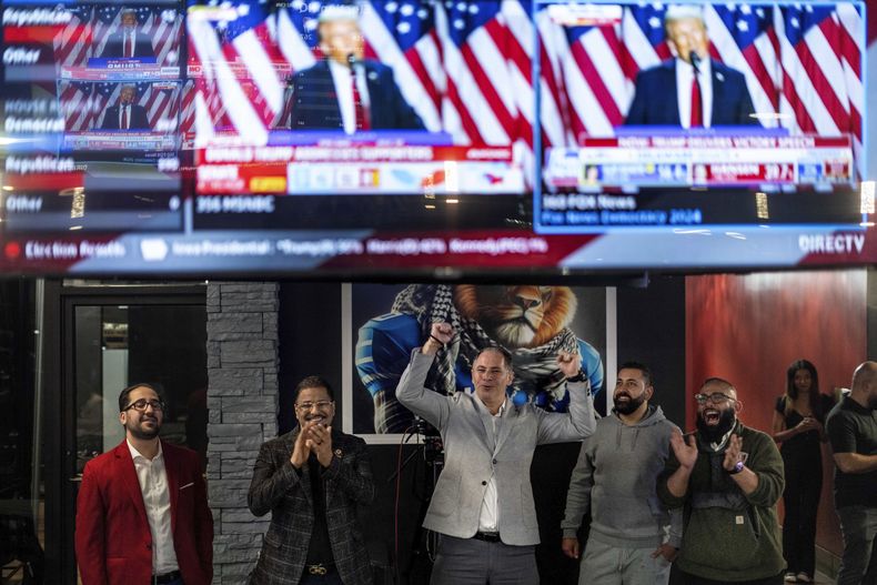 De izq a der, Paul Manni, Sam Alasri, Wasel Yousaf, Waseem Makani y Abrahim Tamimi, en la transmisión de un discurso del candidato republicano Donald Trump en un café en Dearborn, Michigan, el 6 de noviembre de 2024. (AP foto/David Goldman)