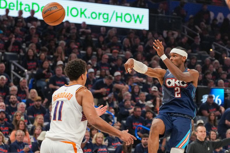 Shai Gilgeous-Alexander (2), del Thunder de Oklahoma City, pasa el balón por encima de Oso Ighodaro (11), de los Suns de Phoenix, durante la segunda mitad del segundo juego de la serie de primera ronda de playoffs del baloncesto de la NBA el miércoles 22 de abril de 2026, en Oklahoma City. (AP Foto/Kyle Phillips)