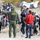 Un agente de la Patrulla Fronteriza da indicaciones a solicitantes de asilo para que esperen en la frontera de Estados Unidos con México, cerca de Tijuana, México, el lunes 8 de mayo de 2023, en San Diego. (AP Foto/Denis Poroy)