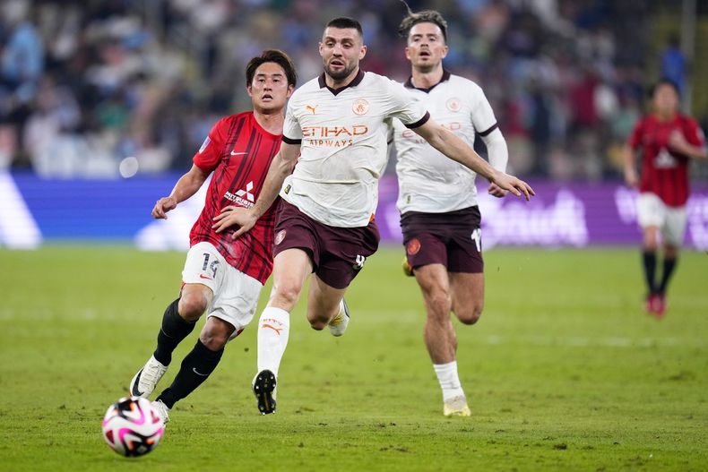 Mateo Kovacic, de Manchester City, empuja a Takahiro Sekine de los Urawa Reds, izquierda, durante la semifinal del Mundial de Clubes de Fútbol entre los Urawa Reds y el Manchester City FC en el estadio Rey Abdullah Sports City en Teda, Arabia Saudí, el martes 19 de diciembre de 2023. (Foto AP/ Manu Fernandez)