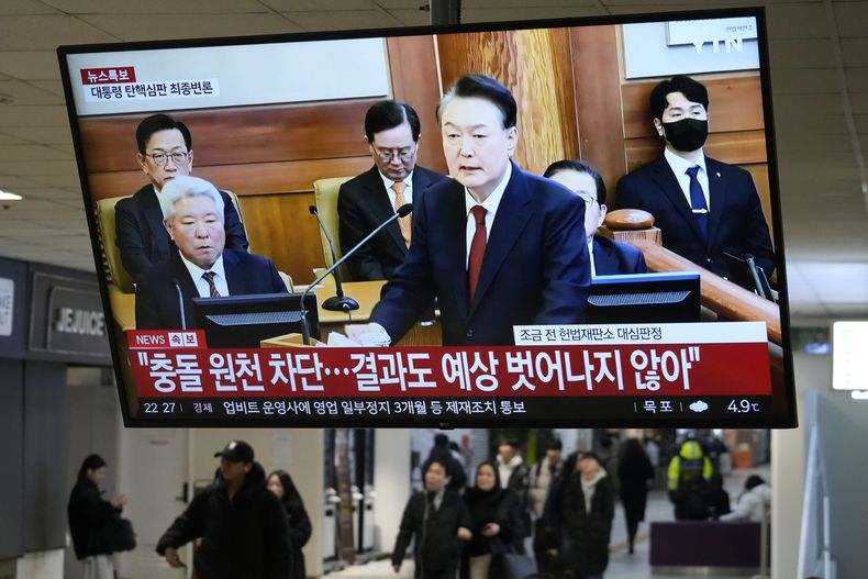 Imágenes televisivas del presidente destituido de Corea del Sur, Yoon Suk Yeol, en la audiencia final de su juicio, transmitidas por un programa de noticias, en una terminal de autobuses de Seúl, Corea del Sur, el martes 25 de febrero de 2025. (AP Foto/Ahn Young-joo)