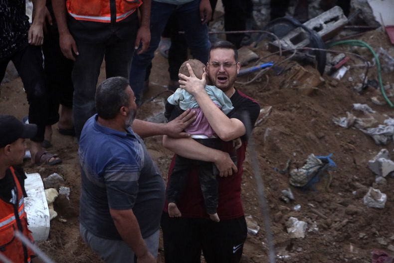 Un hombre palestino llora mientras sostiene en brazos a un bebé muerto encontrado bajo los escombros de un edificio destruido tras ataques aéreos israelíes al campo de refugiados de Nusseirat, en el centro de la Franja de Gaza, el 31 de octubre de 2023. (AP Foto/Mohammed Dahman)