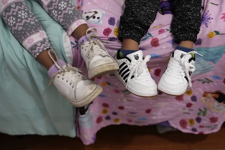 Alexa Llanos, de 7 años, a la izquierda, y su hermano Alexis, de 3, permanecen sentados en una cama de la casa de Lehigh Acres, en Florida, a la que se mudaron en octubre de 2023, cinco años después de haber salido de Venezuela hacia Colombia por amenazas de muerte, el 27 de diciembre de 2023. La de Llanos es una de las primeras familias de migrantes que llegaron a Estados Unidos legalmente bajo un nuevo programa conocido como Oficinas de Movilidad Segura, que busca agilizar el proceso de refugiados. (AP Foto/Rebecca Blackwell)