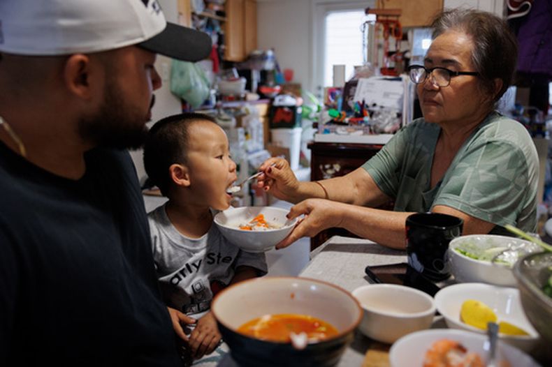 Lien Chang alimenta a su nieto de 2 años, Cairo Miu, con un tazón de arroz junto a su padre, Jack Chang, en su vivienda, el lunes 13 de julio de 2026, en San Francisco. (AP Foto/Juliana Yamada)